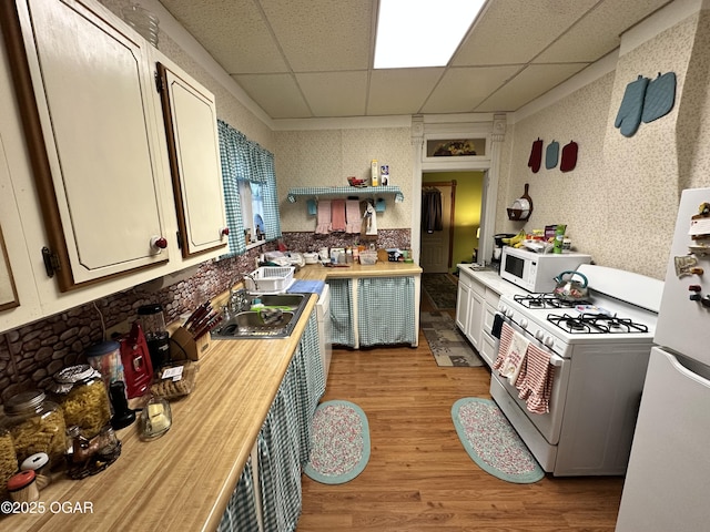301 S 7th St, Sarcoxie, MO 64862 - kitchen featuring a sink, white appliances, wallpapered walls, a drop ceiling, and light wood-type flooring