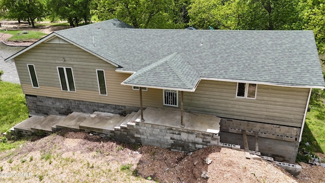rear view of house featuring roof with shingles, a garage, and a patio
