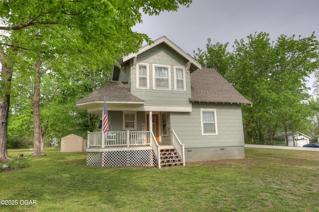 bungalow-style home featuring covered porch, a shingled roof, and a front yard