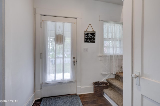 entryway featuring dark wood-style flooring, baseboards, a wealth of natural light, and stairway