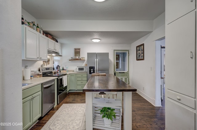 kitchen featuring appliances with stainless steel finishes, green cabinets, under cabinet range hood, and dark wood-style floors