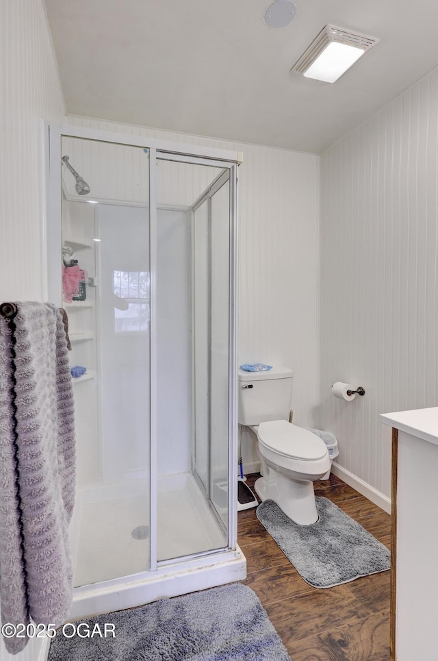full bath with baseboards, a shower stall, toilet, and wood finished floors