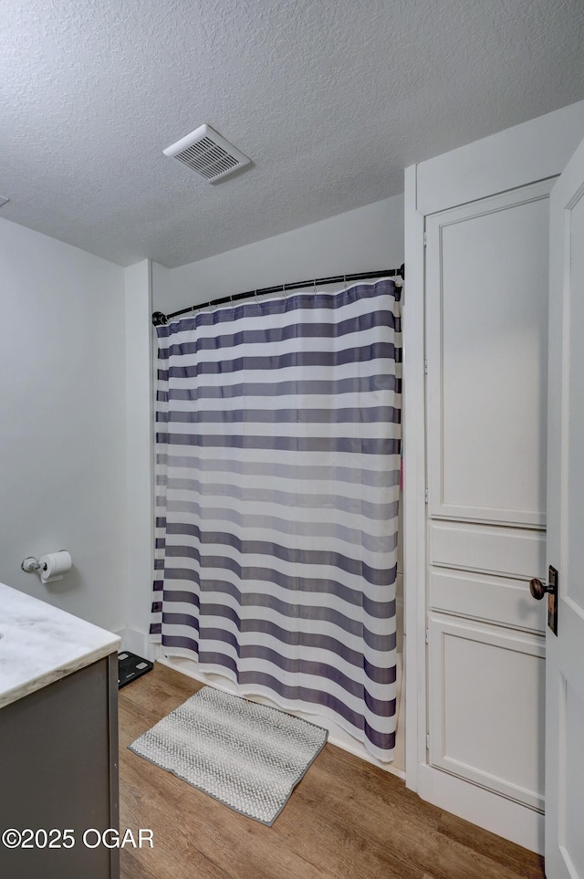 bathroom featuring a shower with curtain, a textured ceiling, visible vents, wood finished floors, and vanity