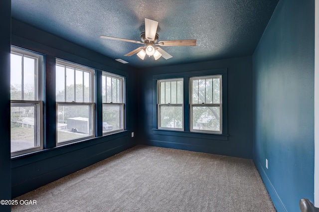 carpeted empty room with a textured ceiling, plenty of natural light, and ceiling fan