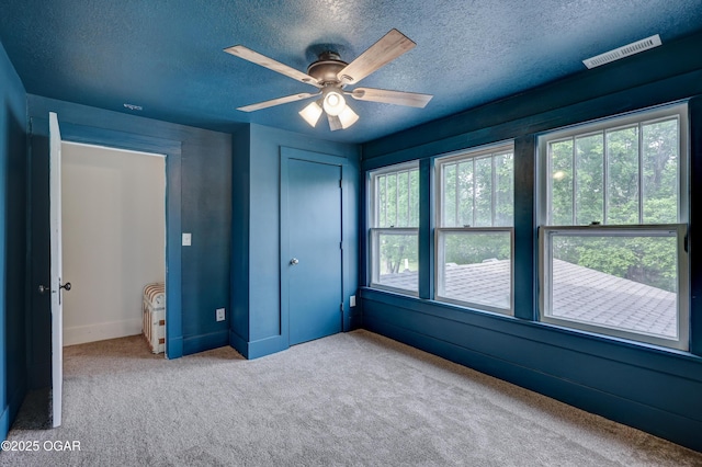 unfurnished bedroom with carpet floors, a textured ceiling, visible vents, and a closet