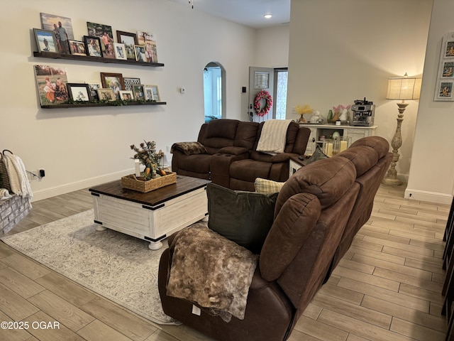 living area featuring arched walkways, baseboards, recessed lighting, and wood finished floors