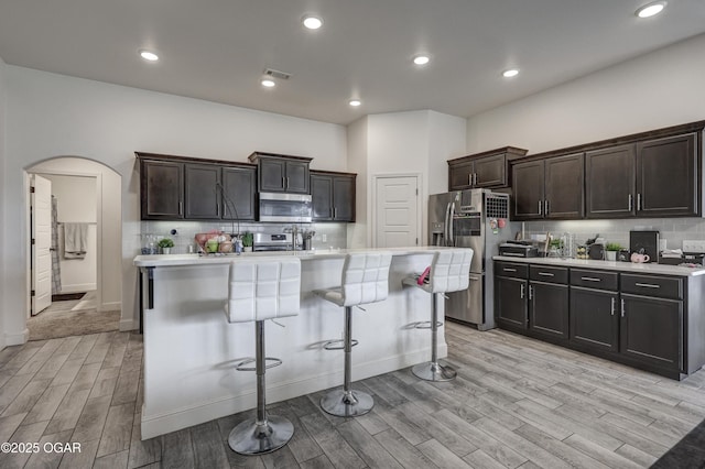 1810 Boyer Pl, Webb City, MO 64870 - kitchen with appliances with stainless steel finishes, arched walkways, light wood-style floors, light countertops, and tasteful backsplash