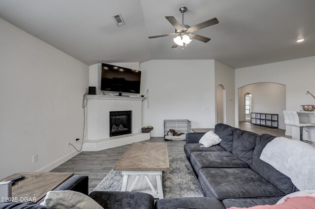 1810 Boyer Pl, Webb City, MO 64870 - living room featuring arched walkways, ceiling fan, wood finished floors, a brick fireplace, and baseboards