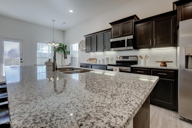 1814 Fountain Rd, Webb City, MO 64870 - kitchen with light stone countertops, appliances with stainless steel finishes, a center island with sink, and a sink