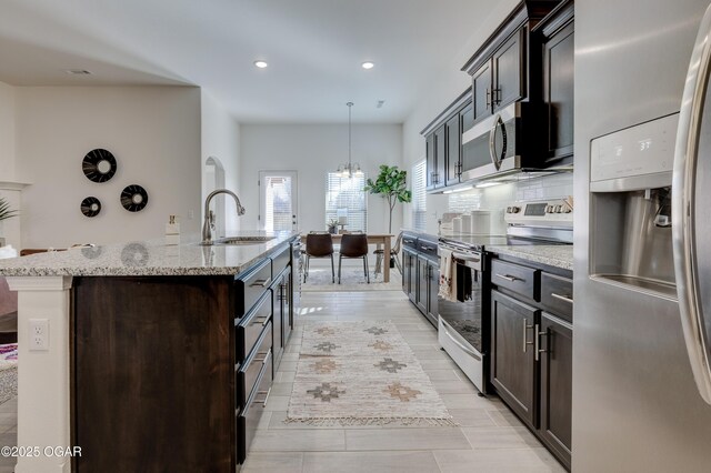 1814 Fountain Rd, Webb City, MO 64870 - kitchen featuring a center island with sink, recessed lighting, light stone counters, a sink, and appliances with stainless steel finishes