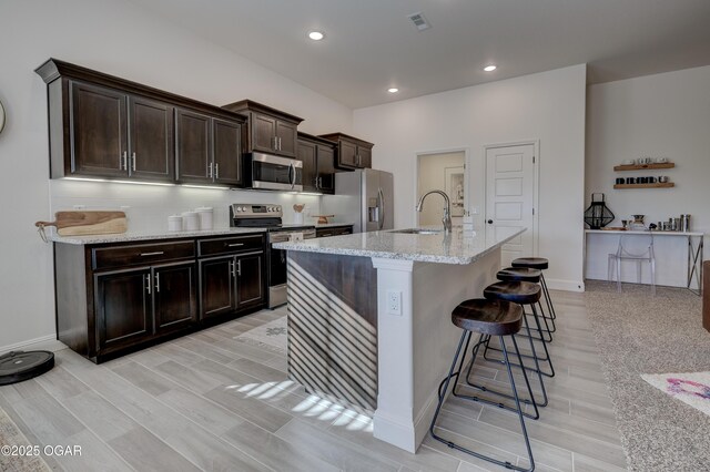 1814 Fountain Rd, Webb City, MO 64870 - kitchen with appliances with stainless steel finishes, a sink, light wood-style flooring, a kitchen bar, and visible vents