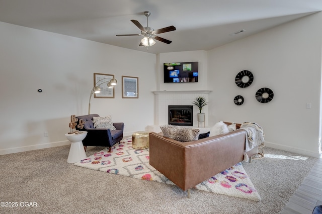 living room featuring ceiling fan, a brick fireplace, baseboards, wood finished floors, and visible vents