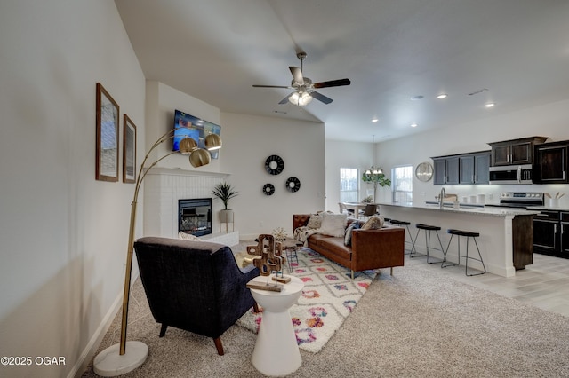 living area with recessed lighting, ceiling fan, baseboards, and a fireplace