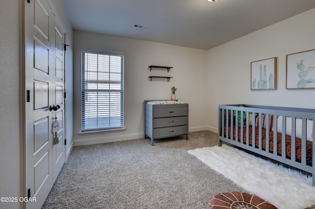 carpeted bedroom featuring baseboards, a nursery area, and visible vents
