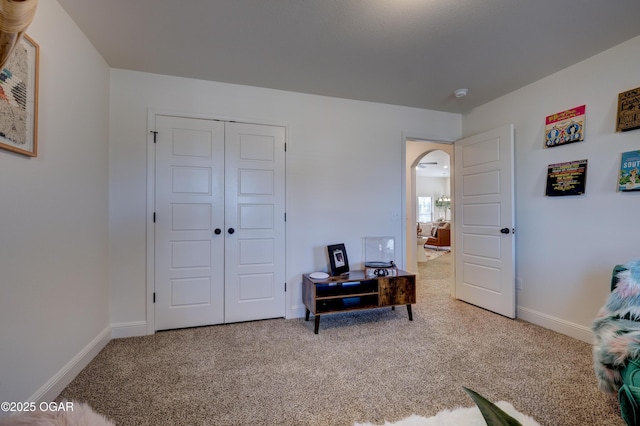 carpeted bedroom with baseboards, arched walkways, and a closet