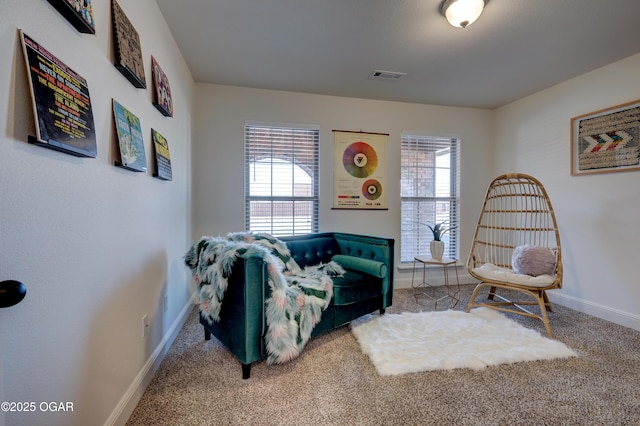 living area featuring baseboards, visible vents, and carpet