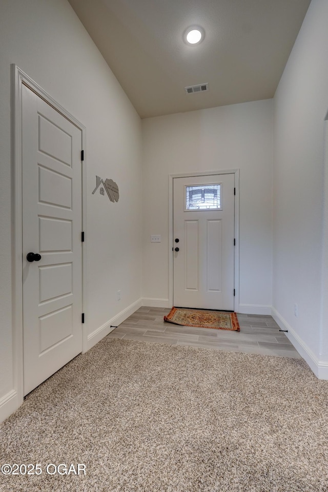 carpeted entryway with baseboards and visible vents