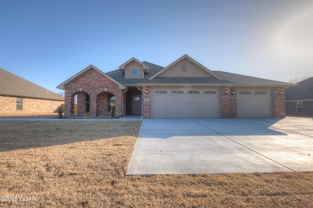 view of front of property featuring a garage, concrete driveway, a front yard, and brick siding