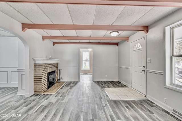 530 N Joplin Ave, Joplin, MO 64801 - unfurnished living room featuring arched walkways, wood finished floors, a fireplace, and beamed ceiling