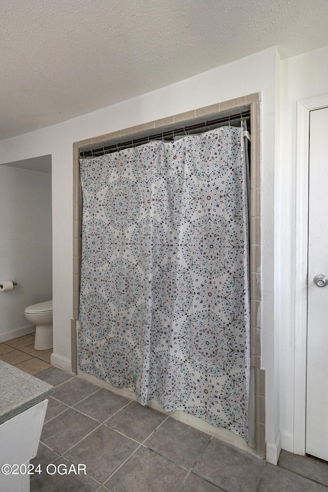 530 N Joplin Ave, Joplin, MO 64801 - bathroom with tile patterned flooring, a tile shower, toilet, and a textured ceiling