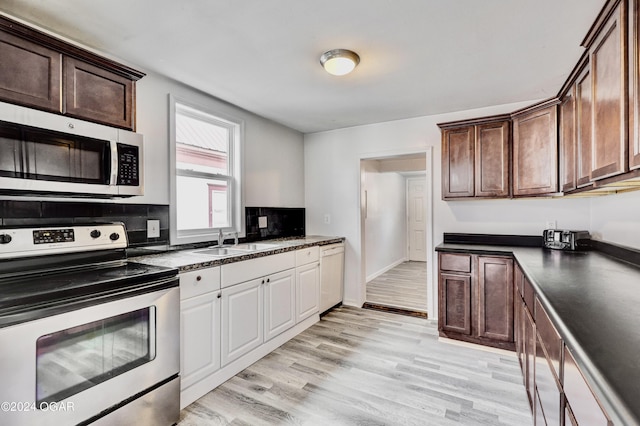 530 N Joplin Ave, Joplin, MO 64801 - kitchen featuring decorative backsplash, dark countertops, appliances with stainless steel finishes, a sink, and light wood-style flooring