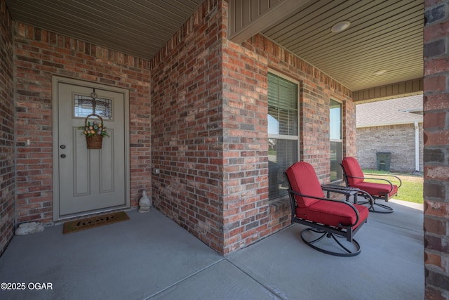property entrance featuring brick siding, a porch, and board and batten siding
