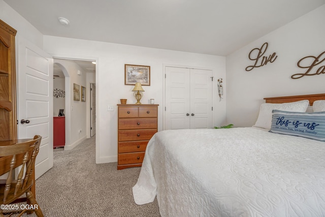 bedroom featuring arched walkways, carpet flooring, a closet, and baseboards