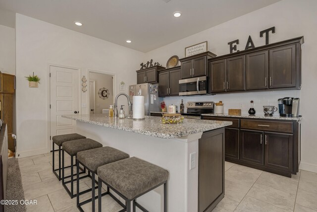 kitchen with stainless steel appliances, tasteful backsplash, light tile patterned floors, an island with sink, and recessed lighting