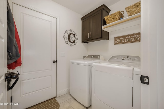 laundry room featuring washing machine and dryer, cabinet space, and light tile patterned flooring