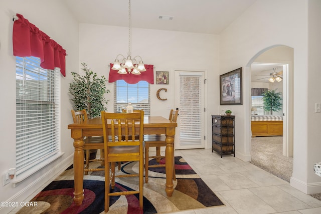 dining space featuring a chandelier, baseboards, ceiling fan, arched walkways, and light tile patterned floors