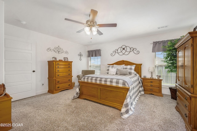 bedroom featuring multiple windows, light colored carpet, and a ceiling fan