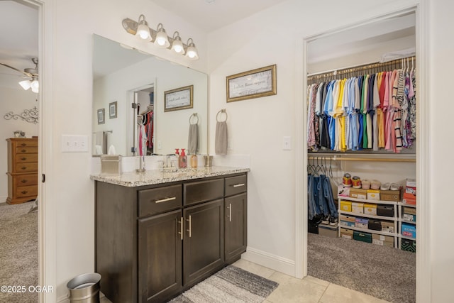 bathroom with a ceiling fan, a walk in closet, and vanity