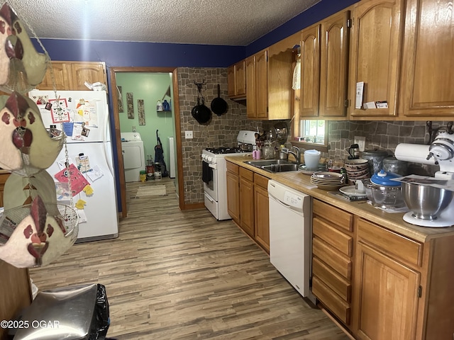 1793 8000th Rd, Oswego, KS 67356 - kitchen featuring washer / dryer, white appliances, light wood-type flooring, light countertops, and a sink