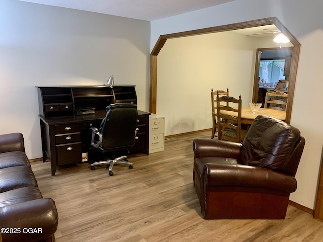 office featuring baseboards, a ceiling fan, and light wood finished floors