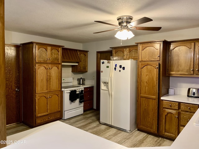 kitchen with brown cabinets, light wood-style floors, white appliances, light countertops, and a ceiling fan