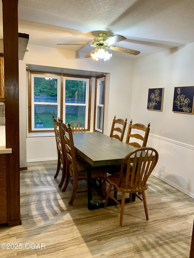 dining space with baseboards, ceiling fan, and a textured ceiling