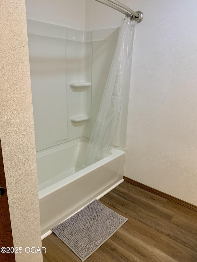 bathroom with shower / bath combo with shower curtain, baseboards, and wood finished floors