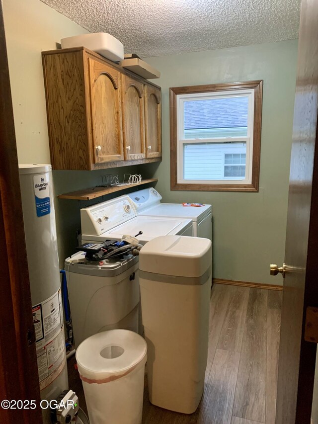 washroom with washer and dryer, cabinet space, a textured ceiling, water heater, and wood finished floors