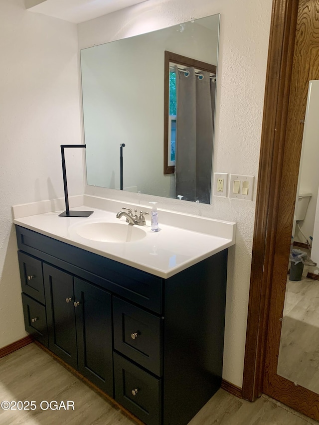 bathroom featuring vanity, baseboards, and wood finished floors