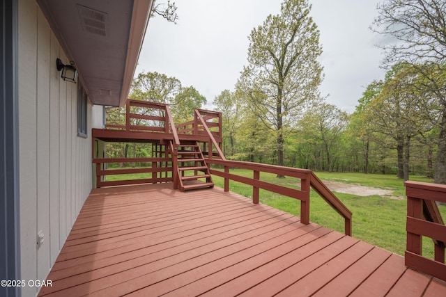 wooden terrace featuring a lawn and stairway