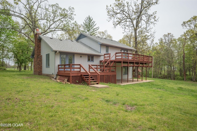 rear view of property with a lawn, a wooden deck, a shingled roof, and a chimney