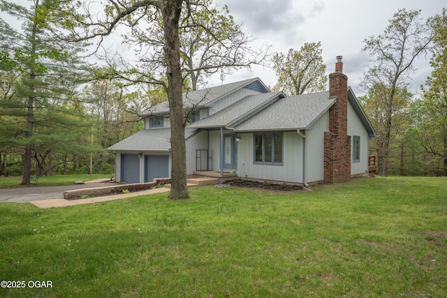 view of front of house featuring a shingled roof, a chimney, driveway, and a front lawn