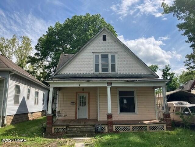 back of property with a yard and covered porch