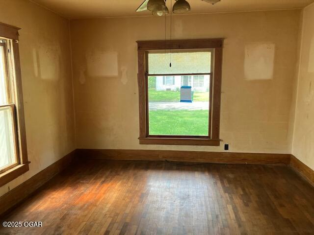 spare room with baseboards and wood finished floors
