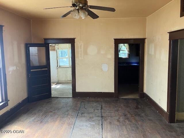 empty room featuring wood finished floors, baseboards, and ceiling fan