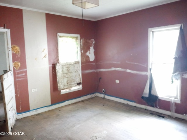 unfurnished room featuring visible vents, baseboards, and ornamental molding
