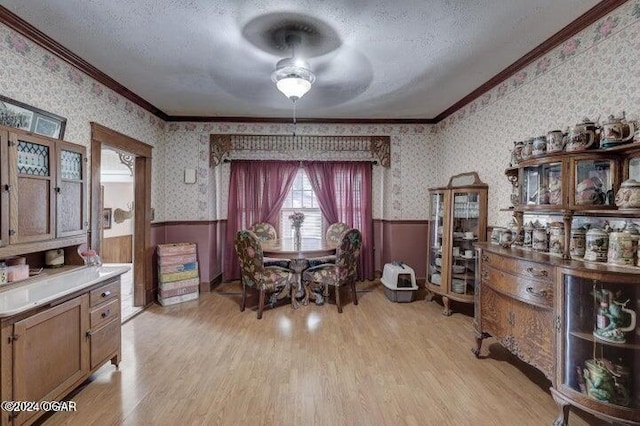 1418 Cleveland Ave, Baxter Springs, KS 66713 - dining room featuring ornamental molding, a wainscoted wall, wallpapered walls, light wood-style floors, and a ceiling fan