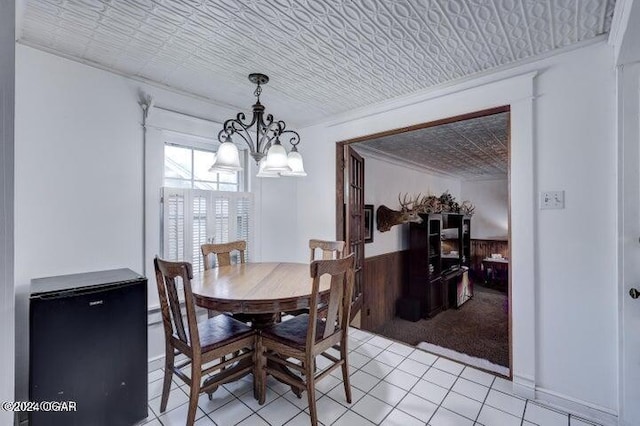 1418 Cleveland Ave, Baxter Springs, KS 66713 - dining space with a chandelier, wainscoting, light tile patterned floors, and wood walls
