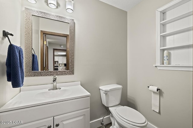 half bath with baseboards, vanity, and toilet