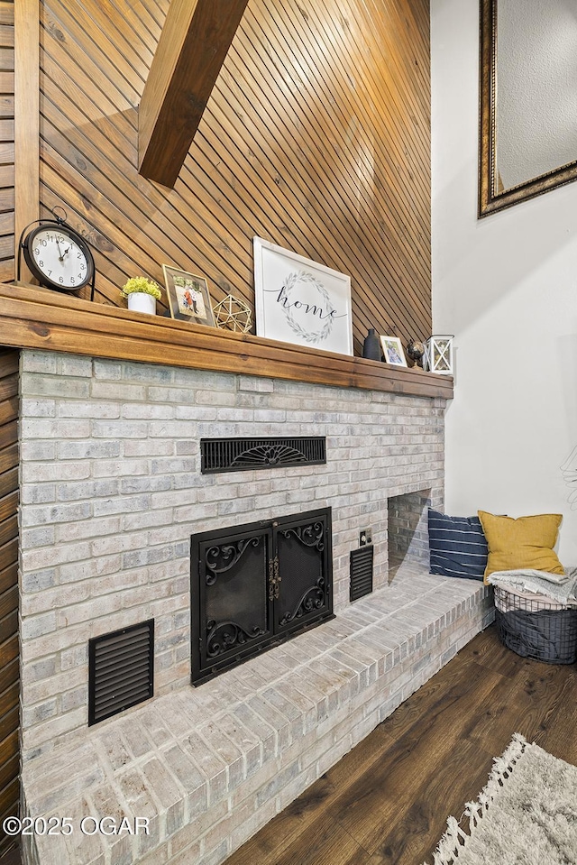 living room with wooden walls, wood finished floors, and a brick fireplace